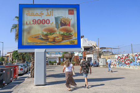 Pedestrians walk past a McDonalds chicken burgers advertising board in Beirut.