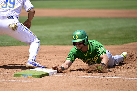 Ryan Cooney (12) slides into first base during an NCAA baseball game against the Oregon Ducks and the UCLA Bruins at Jackie Robinson Stadium on May 10, 2026 in Los Angeles, California.