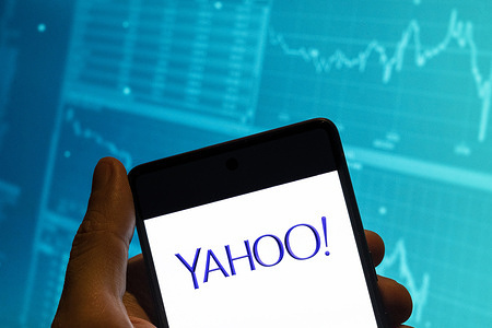 In this photo illustration, the American web services provider company Yahoo! logo is seen displayed on a smartphone with an economic stock exchange index graph in the background.