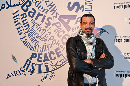 Palestinian theatre director and actor Ihab Zahdeh is seen in front of a billboard for the 11th Amed International Theatre Festival.