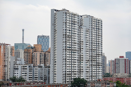 General view of Beijing showing a large white high - rise residential building, with various other buildings in different colors and styles in the background, along with some greenery.