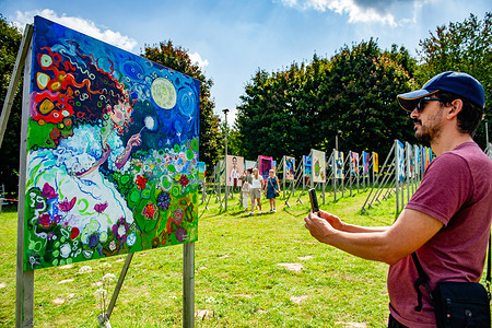 A man takes photos of one of the paintings. The colorfield Performance features 336 paintings that refer to the number of days between D-Day (Invasion of Normandy) and Nazi Germany's surrender. The goal is to pursue a large colourful unity conceived out of multiple individual contributions. Dutch artist Dirk Hakze is the organizer of this international artistic project that exhibits paintings resting on easel-like structures forming a large V shape in the countryside landscape. This year, the theme is peace and victory.