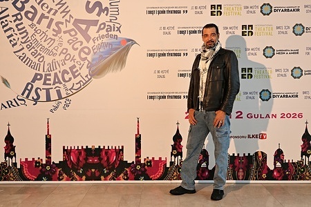 Palestinian theatre director and actor Ihab Zahdeh is seen in front of a billboard for the 11th Amed International Theatre Festival.