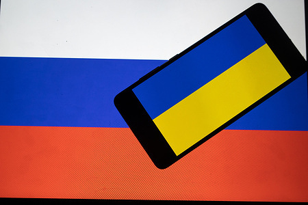 In this photo illustration, the Ukrainian flag is seen on a mobile screen in front of a Russian flag.