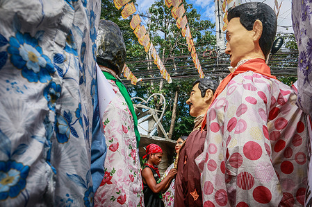 A man seen dressing a papier-mache statue during the Higantes Festival grand parade. The locals celebrate their town's festival for the first time after two years of suspension due to the pandemic. The Higantes or papier-mache giants were first believed to have been made by local farmers as a form of protest against their landlords during the Spanish colonization era. The giant papier-mache puppets measure from four to five feet in diameter and ten to twelve feet in height and handlers can only control the giants from inside of them.