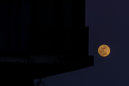 The full moon seen rising above the horizon in the sky near the Vasco da Gama Bridge and the Tejo River. The Pink Moon as it is known marks the beginning of spring in the Northern Hemisphere and the blooming of some wild plants.