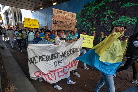 Presumably foreign students march along Rijnstraat while holding a banner, Ukrainian flag and placards during the protest. Putin’s invasion of Ukraine, saw not only the mass evacuation of its indigenes people, but also the evacuation of its foreign student body studying in that country. Rather than returning home, most fled to neighbouring Europe and four-thousand plus entered The Netherlands. At the time they were granted asylum with similar rights as awarded to Ukrainians nationals. Students who had submitted asylum requests now consider this was a form of entrapment; they now see their applications rejected and are now facing deportation. The protesters demand the same rights awarded to Ukrainian asylum citizens, and also want the right to stay and continue their studies in Netherlands. They have until 4 September 2023 to leave Netherlands voluntarily or face deportation. Those that leave prior to this date are given a Five-thousands Euro cash incentive and a one-way ticket home, a large majority accepted this offer; those that remain after this date will be treated as illegal immigrants.