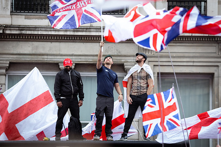 Protesters draped in St Georges flags watch the rally on top of a bus stop. Thousands of people joined Tommy Robinson's Unite The Kingdom march in the city. A counter-demonstration was also organised by Stand Up To Racism, which saw 16000 police officers deployed to keep the peace. Up to 150,000 people are believed to have joined the march.