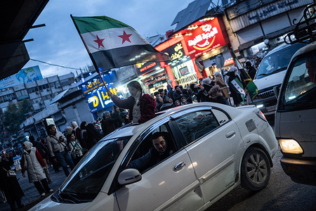 A person waves a flag during celebrations in the streets of the Syrian capital, Damascus to mark one year after the fall of the Baath Party and Assad regime. Syrians fill the streets of central Damascus, waving flags and singing patriotic songs to a background of fireworks, flares and car horns in celebration of the first year since the fall of the Assad regime.