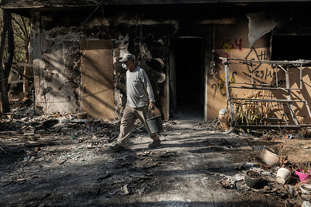One of the archaeologists carries remains of the houses burned in the attack on October 7 to be examined by specialists. Nir Oz, a kibbutz in southern Israel, was a target of a surprise attack by the Palestinian armed group Hamas on October 7. The attack resulted in 140 casualties, including 100 residents killed and 300 injured. The town now resembles a ghost town with ruined houses and abandoned fields. Given that some bodies are still unrecovered, a team of archaeologists has been deployed to Nir Oz to retrieve the charred remains of the attack's victims. The goal is to identify all the victims and return their remains to their families.