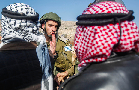 An Israeli soldier argues with the Palestinian protesters during the demonstration against Israeli settlements in the village of Beit Dajan near the West Bank city of Nablus.