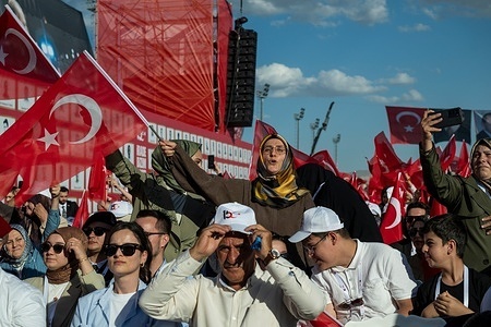 A man seen wearing a cap with the writing 15 July. Turkish President Recep Tayyip Erdoğan delivers a speech at Başkent Millet Bahçesi (Capital National Garden) during the 10th anniversary commemoration of July 15 Democracy and National Unity Day. The event is attended by government officials, media representatives, and members of the public.