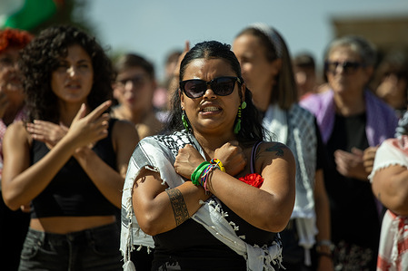 A woman makes protest signs with her hands clasped at a demonstration. Feminist groups have called for a rally at the Temple of Debod to demand food, life and dignity against the genocide in Palestine. They have also denounced the escalating violence in Gaza and sent support to the flotilla. They dressed in black and wore keffiyehs under the slogan "Feminist resistance for a free Palestine!"