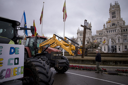 A farmer driving his tractor carrying a giant cross as he passes in front of the Cibeles Palace in the center of Madrid, during a massive demonstration of farmers and ranchers with tractors through the streets of Madrid, protesting the cuts to the future Common Agricultural Policy (CAP) and the recent EU-Mercosur trade agreement.
