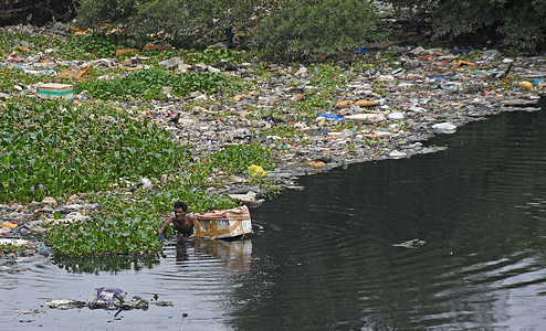A man is seen collecting waste materials on the bank of Mithi River. Mithi River originates from Vihar and Powai lake and passes through the city of Mumbai before it meets the Arabian sea. It is heavily polluted and becoming narrower due to urban development and slums mushrooming on its bank. The river is polluted with waste from nearby slums and solid waste like plastic, construction debris, household garbage and cattle waste and nearby industries discharge hazardous wastes and effluents thereby, adding to water pollution and danger to marine life in a big way. pollution has reduced its water carrying capacity leading to stagnation and high risk of flooding in and around the slums on its bank especially during the monsoon season.