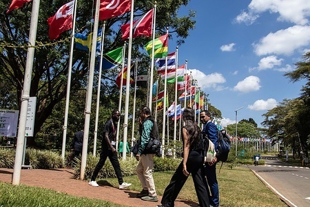 Delegates walk past UN member state flags during the United Nations Environment Assembly (UNEA) in Nairobi, where countries are expected to adopt resolutions addressing biodiversity loss, pollution, and climate change.