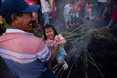 A devotee lifts his child over the fire as part of the celebration during the festival. Ghantakarna festival is a celebration of the defeat of the mythical demon Ghantakarna, chasing the evil spirits and bringing good fortunes.