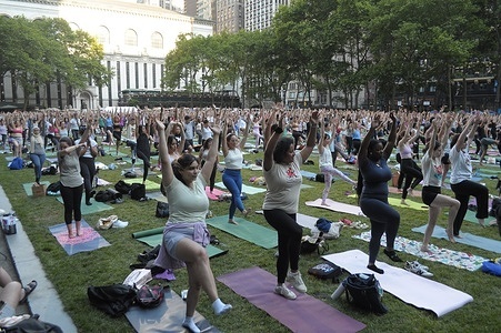 People participate in a group yoga class on the lawn in Bryant Park, Manhattan, New York City.