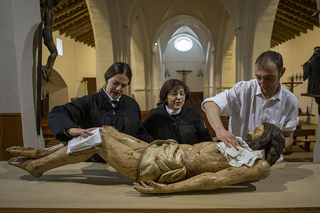 Members of the brotherhood of Our Father Jesus of Nazareth and the Patronage of Saint Joseph clean 'Christ' before placing him on the cross in front of the altarpiece of the Church of San Lorenzo in preparation for the mass of Adoration of the Cross and the Act of Detachment with Christ during Good Friday activities in Sahagun.