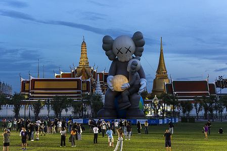Visitor seen near the 18-meter-high inflatable art sculpture " COMPANION", titled "KAWS: HOLIDAY THAILAND," by renowned artist KAWS (Brian Donnelly), being displayed at Sanam Luang in Bangkok.