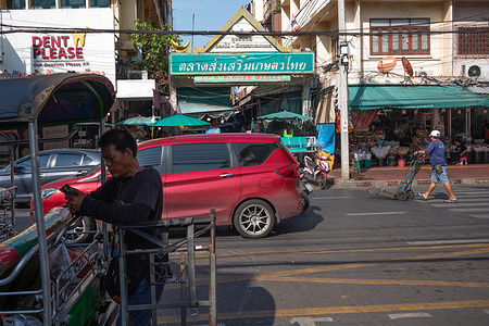 A man stands next to his trolley, waiting outside the flower market in Bangkok.