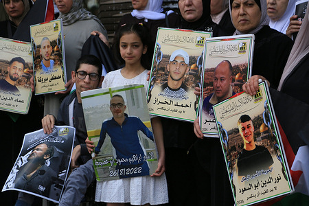 Palestinians hold up pictures of Palestinian prisoners during a solidarity march in front of the entrance to the commercial market in downtown Nablus demanding the release of their sons detained in Israeli prisons.
