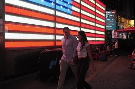 People walk past a lighting installation of the American flag in Times Square, Manhattan, New York City.