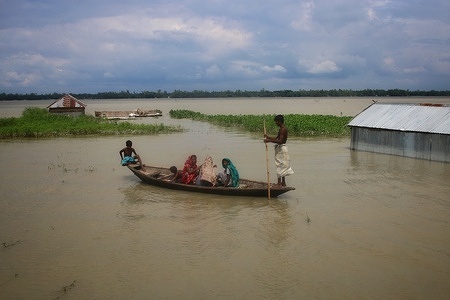 A flood affected family travelling on a boat on a flooded area in Tangail.
Around 129,000 villagers are marooned and 3,686 hectares of croplands have been submerged in Tangail due to floods.