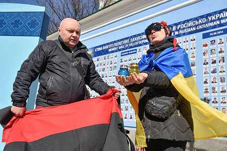 People with lamps and flags of Ukraine mourn at the wall of memory. People gathered at the Wall of Memory for "Volunteers Day", in commemoration of those who died in the Russian-Ukrainian war.