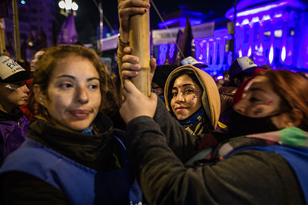 A girl looks at the camera while two companions hold a banner in front of the National Congress during the demonstration. Seven years after the first historical mobilisation against femicides and gender-based violence, the “Not one Less” march returned to the streets of the City of Buenos Aires, with thousands of women protesting against sexist violence and under the slogan “Alive, free and debt-free, we love each other!”