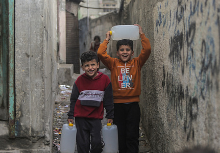 Palestine refugee children carry drinking water to their homes at Jabalia camp in the northern Gaza Strip.