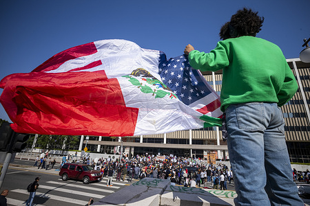 A man holds flag as community organizers protest outside the Federal Building following an immigration enforcement operation by federal authorities.
