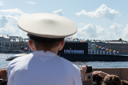 Spectators watch the military ships on the Neva River during the annual Navy Day parade in St. Petersburg.
