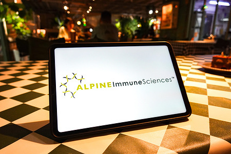 In this photo illustration, the Alpine Immune Sciences logo is seen displayed on the screen of a tablet.