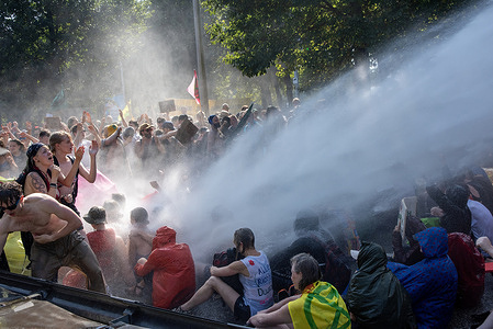 The police deploys water cannon on the protesters while they are sitting on the motorway during the demonstration. Thousands of Extinction Rebellion climate activists blocked the A12 motorway in The Hague, Netherlands. They were trying to pressure the government to immediately stop investing in fossil fuels.