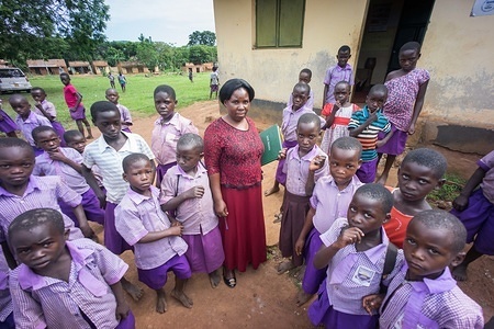 Pupils are seen standing staring with their teacher.
Primary school students on their last day of term in a local school near the town of Hoima in western Uganda.