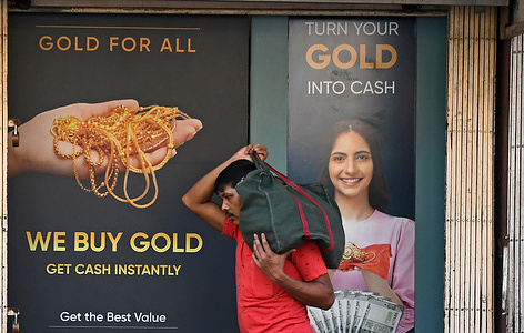 A man carries a cloth bag on his shoulder as he walks past a poster outside a jewellery shop. Indian Prime Minister Narendra Modi appealed the citizens to avoid buying gold for at least a year in order to protect the foreign reserves and strengthen the rupee. High imports of gold combined with the rising price of oil and fuel is putting pressure on the economy due to the ongoing tension between US-Iran-Israel.