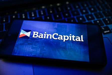 In this photo illustration the Bain Capital logo is displayed on a smartphone on the top of a laptop.