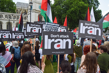 Protesters hold 'Don't attack Iran' placards and Palestinian flags during the demonstration in Parliament Square. Crowds gathered in protest against bombing Iran and in support of Palestine, as Israel continues its attacks on Gaza and launches attacks on Iran.