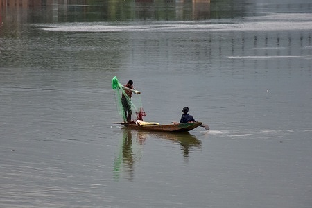 A fisherman (L) prepares to throw net in River Jehlum during rainfall in Srinagar, the summer capital of Jammu and Kashmir.