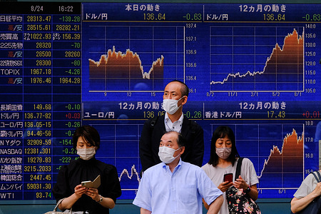People wearing masks stand in front of an electronic board displaying various countries' stock indexes, including the Russian Trading System (RTS) Index, which is empty, outside a brokerage in Tokyo.
