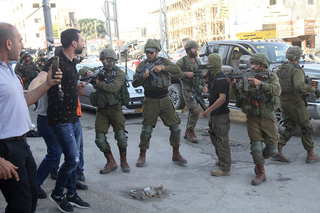 Israeli soldiers aiming at Palestinians while protecting Jewish settlers during a "March For Flags" in the middle of the market in the town of Hawara, south of Nablus in the West Bank.