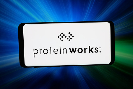 In this photo illustration, the logo of company Protein Works (Class Delta Ltd.) is displayed on a smartphone in front of abstract background on computer screen.