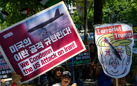 A protester holds a placard and a caricature of U.S. President Donald Trump protesting against U.S. bombing strikes on Iran during a solidarity rally with Palestinians.