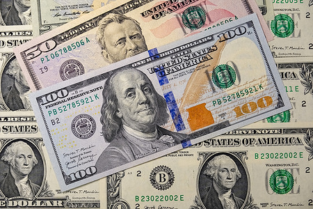 In this photo illustration, A $100 bill (Benjamin Franklin) is placed over smaller US bills.