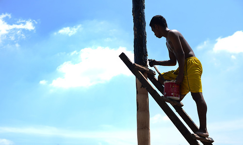 A man seen getting the pole ready for the participants to climb before the event.
Participants climb greased poles to collect prizes during a “Panjat Pinang” event organised in celebration of Indonesia's 73rd Independence day in Medan.