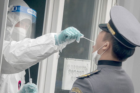 A nurse wearing a personal protective equipment suit (PPE) takes a swab sample from a cadet of the Korea Military Academy during a free covid-19 testing at a makeshift clinic.