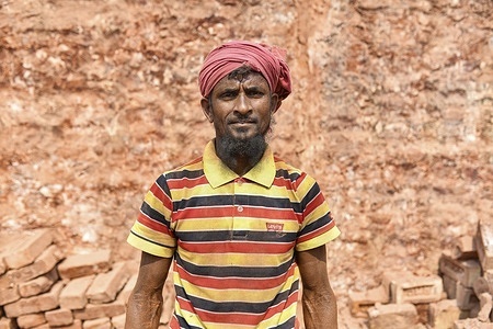 A brick field worker is covered in thick red dust from fired bricks in Bhola.