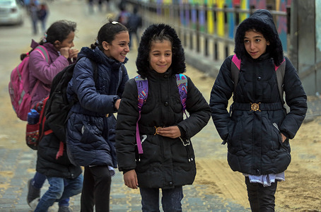 Palestinian students play outside the school as they return home during inclement weather in Gaza City.