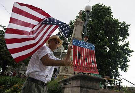 A demonstrator holds the American flag upside down outside the Monroe County Courthouse during the “'Good Trouble Lives On'” march and rally. The event was organized by Bloomington 50501, the NAACP Monroe County Branch, the University Alliance for Racial Justice, and the League of Women Voters of Bloomington–Monroe County.